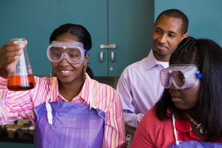 African teenage girl examining experiment in chemistry lab