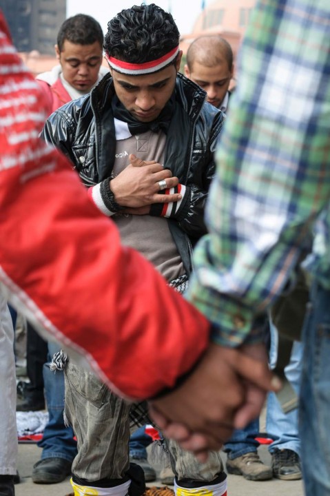 Christian Egyptians, holding hands in the foreground, form a chain around Muslim Egyptians as the Muslims pray during Friday prayers in Tahrir Square 2011.