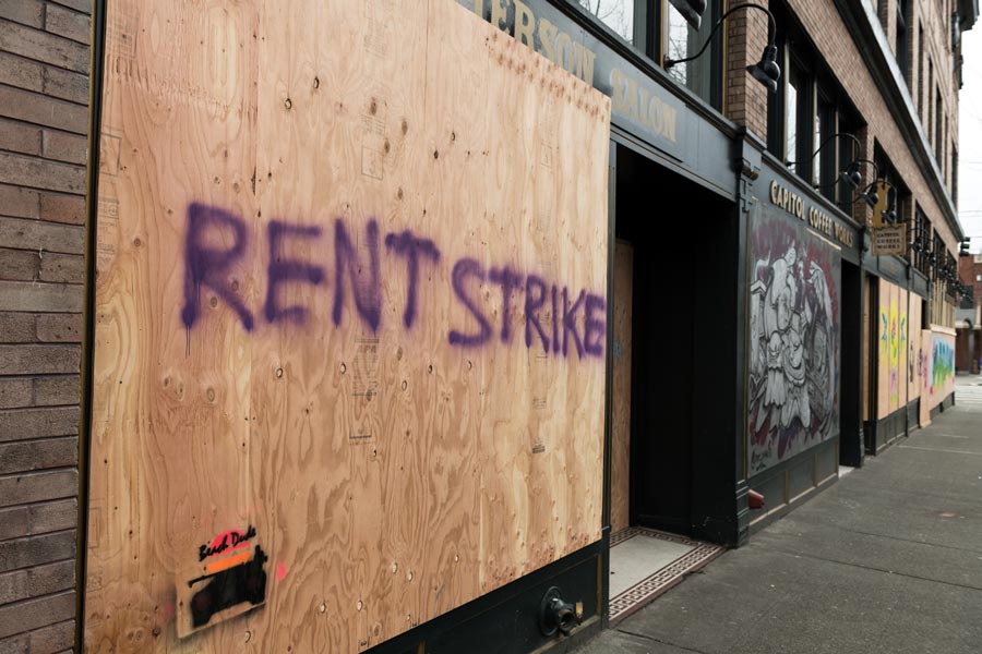 Seattle, USA – March 31, 2020: A boarded up business with ’rent strike’ painted on it.