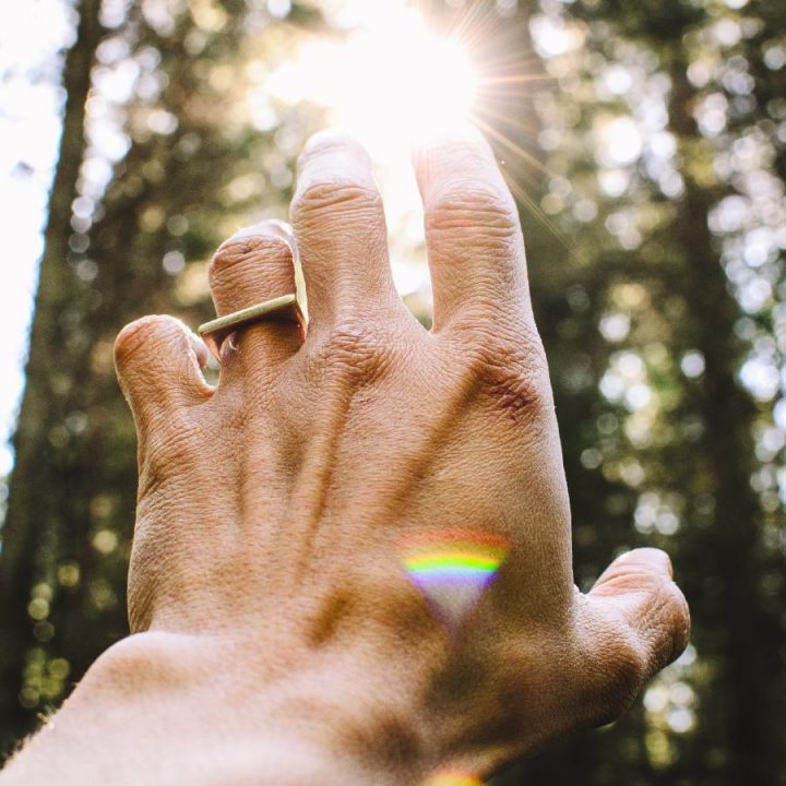 An image of a man reaching up to the sunlight